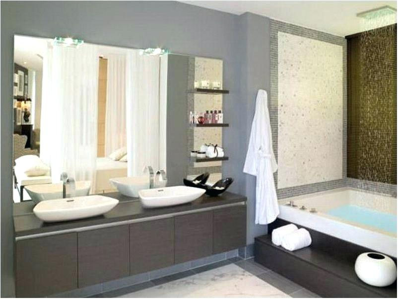 Modern bathroom in Madison, WI with double sinks, a large mirror above, and sleek dark cabinets below. A soaking tub with folded towels and a robe on a nearby hook is located next to a textured wall. Shelves hold toiletries and decorations. The overall design complements recent exterior renovations for contemporary appeal.