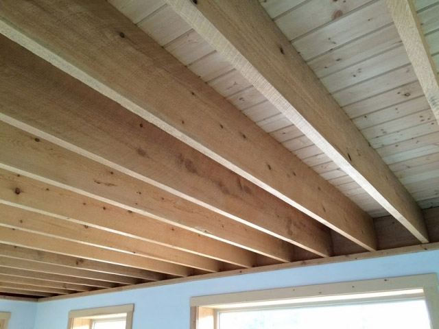 Exposed wooden ceiling beams in a modern room with natural light coming through multiple windows in Madison, WI. The beams and ceiling panels are made from light-colored, unfinished wood, giving the space a rustic yet contemporary feel that's perfect for complementing exterior renovations.